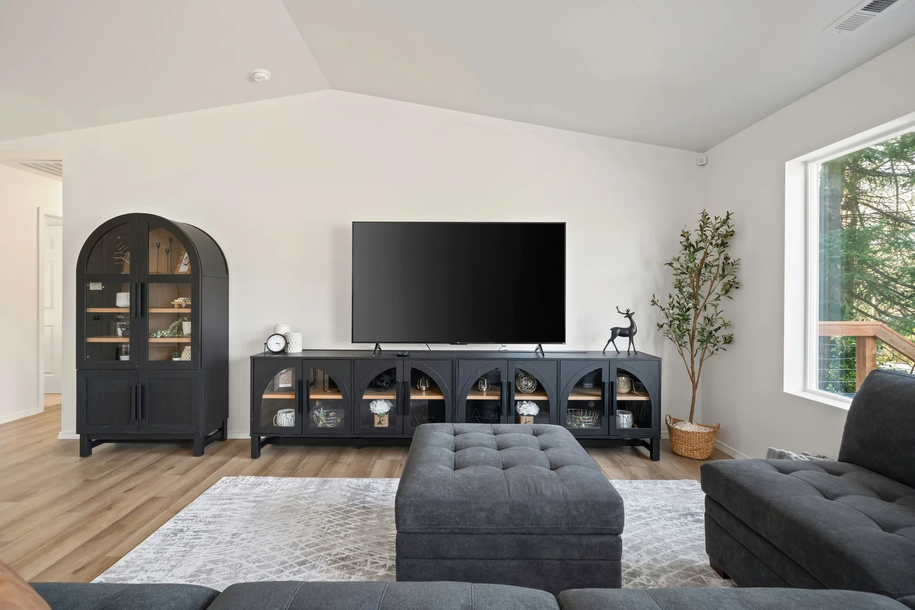 Una sala luminosa con televisor, asientos oscuros y una ventana grande.