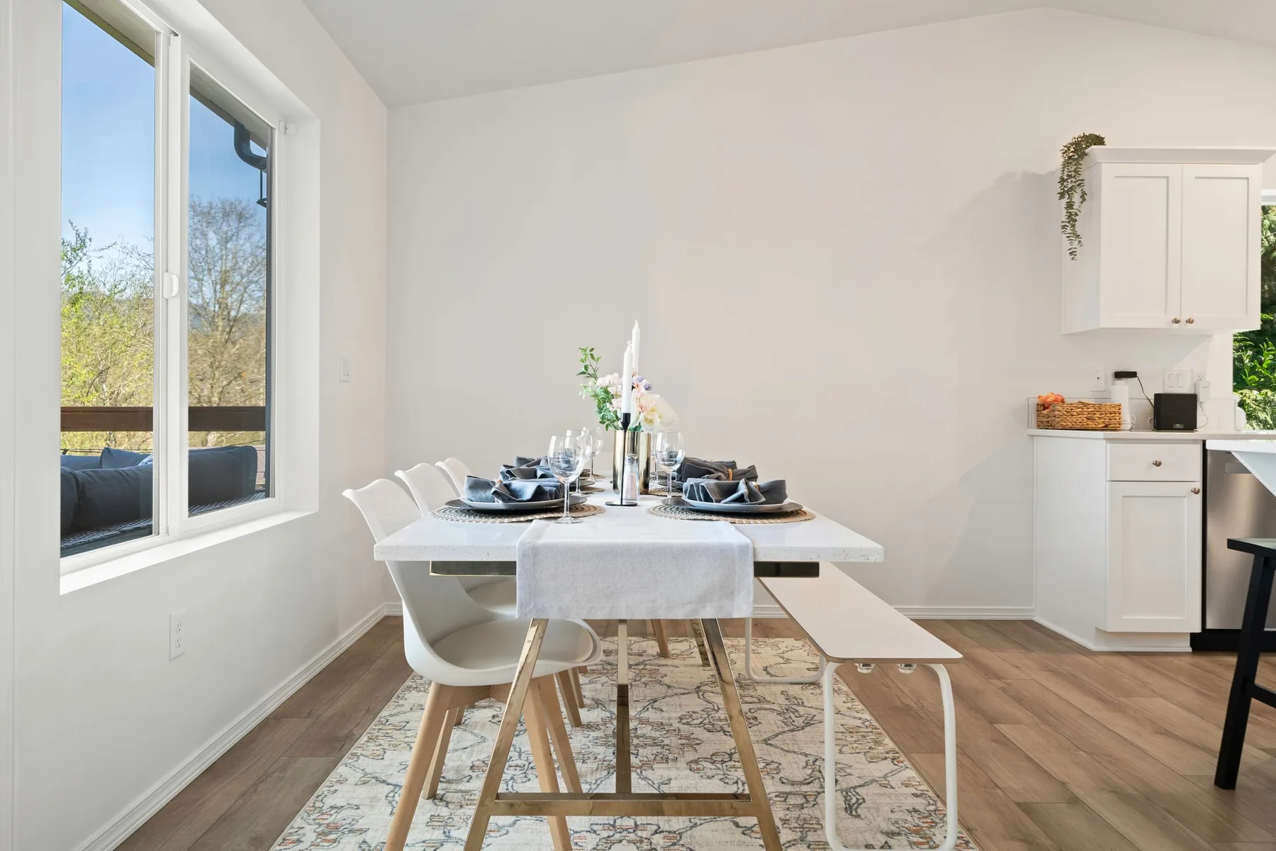 Un comedor luminoso con una mesa puesta junto a grandes ventanas.