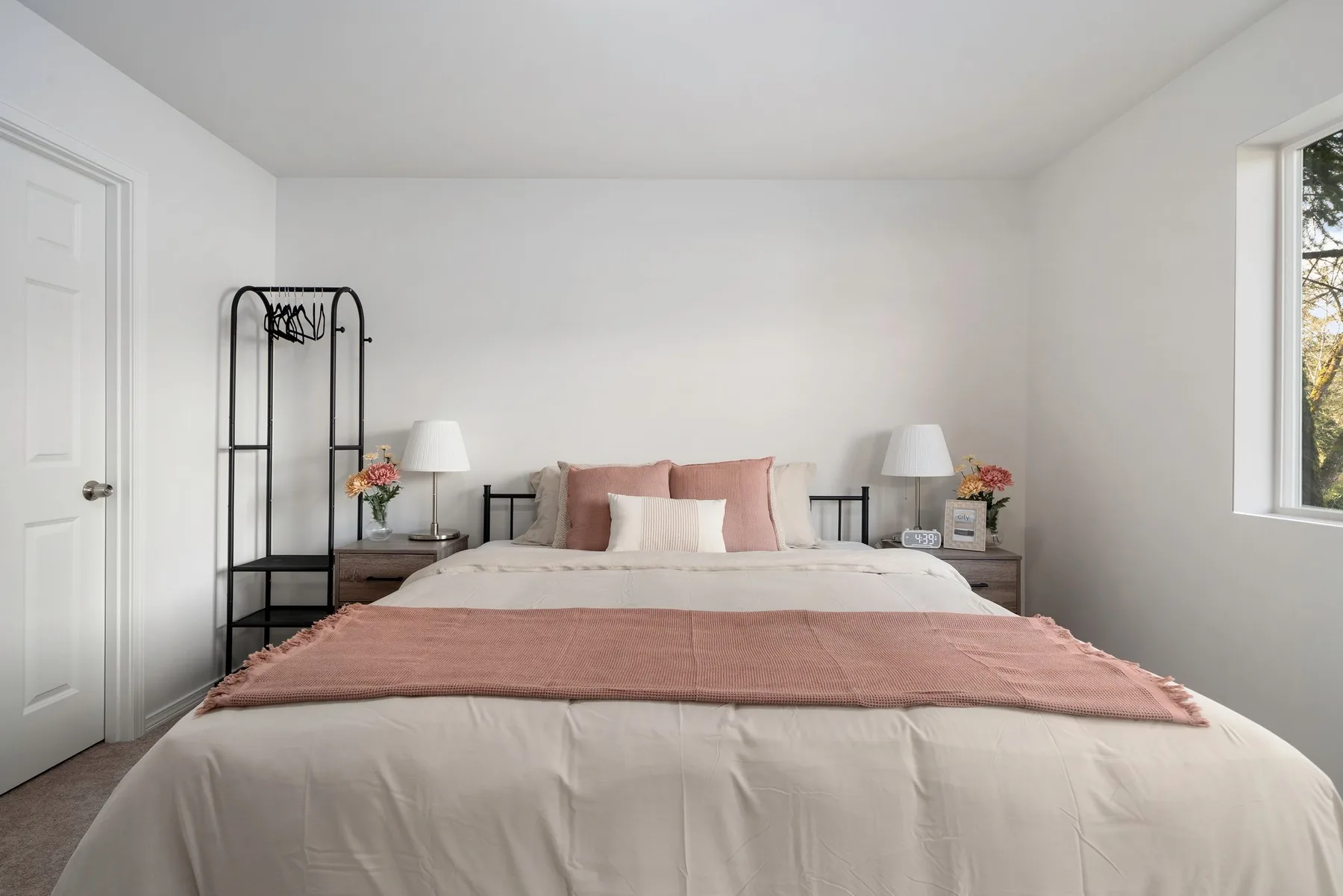 Un dormitorio luminoso con una cama tendida y detalles rosados.