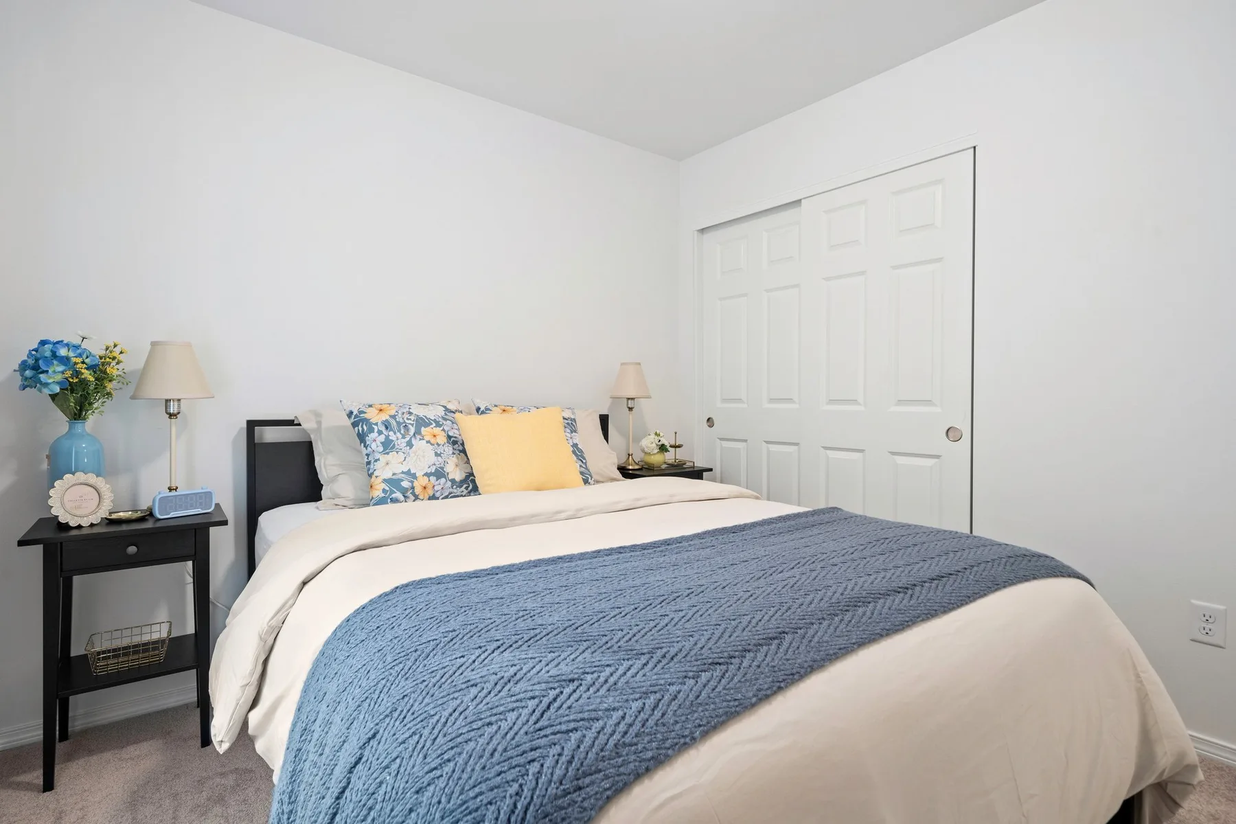 Un dormitorio con una cama bien tendida y una colcha azul.