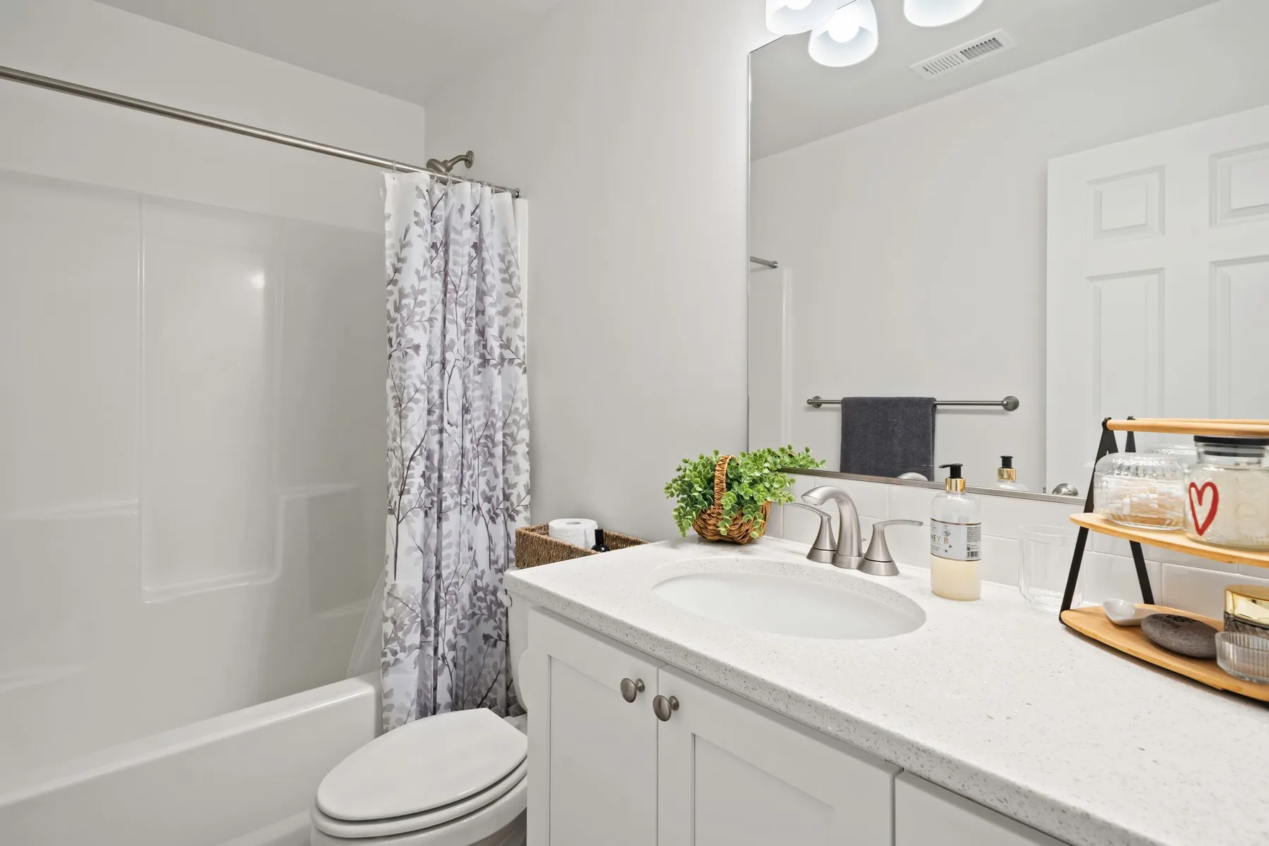 Un baño luminoso con bañera, cortina de ducha y lavabo con mueble.