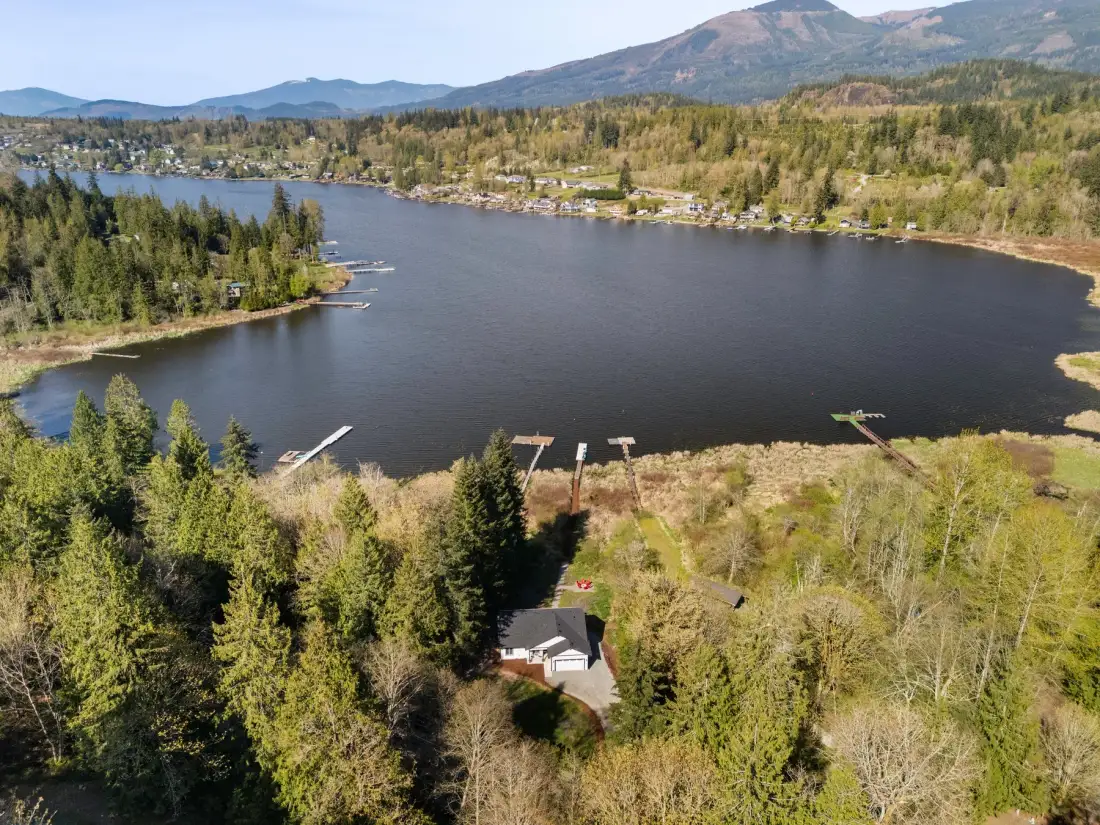 Vista aérea de un paisaje junto al lago, con bosque, muelles y montañas.