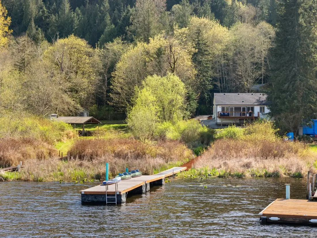 Una casa junto al lago y muelles de madera bordean una orilla boscosa.
