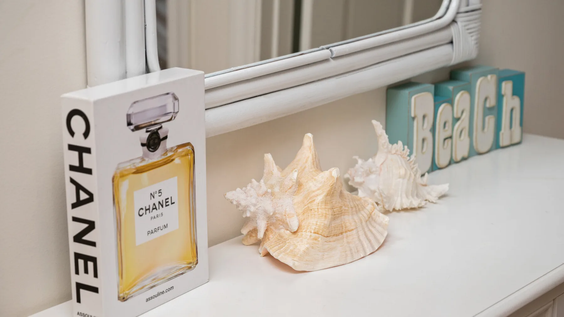 A bathroom vanity displays seashells and decorative items beneath a mirror.