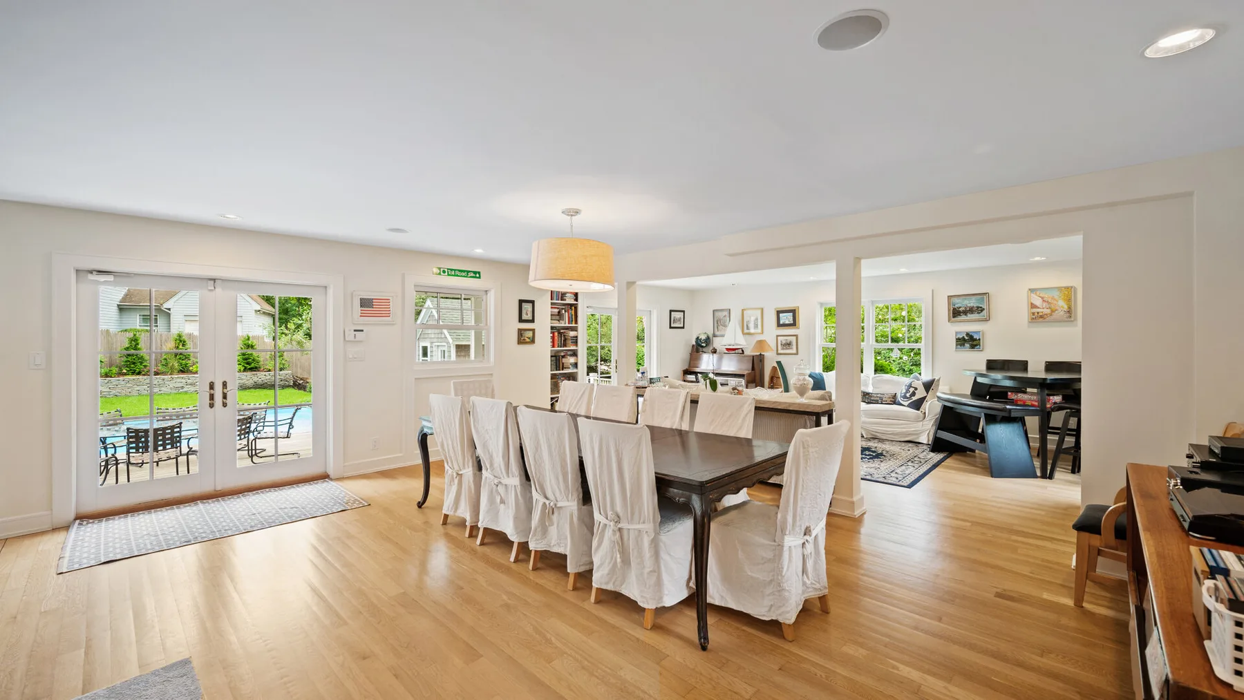 A bright dining and living area with a long table and large glass doors.