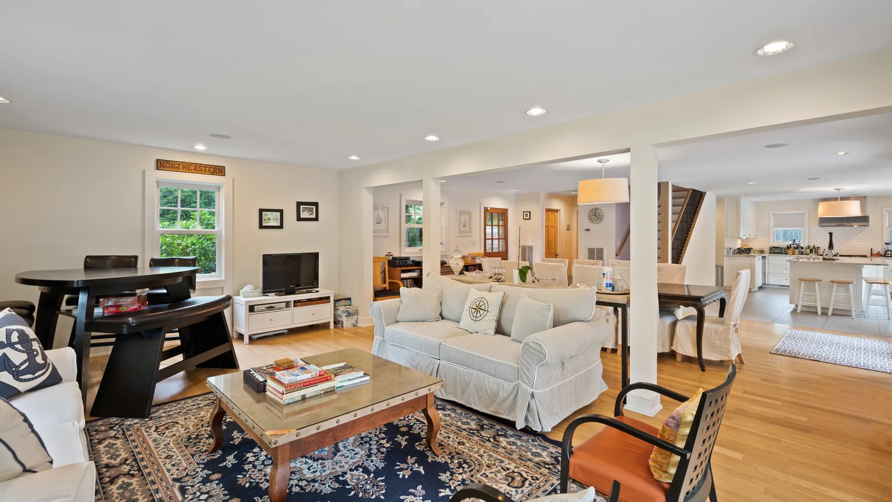 An open living room with light-colored seating, a coffee table, and a patterned rug.