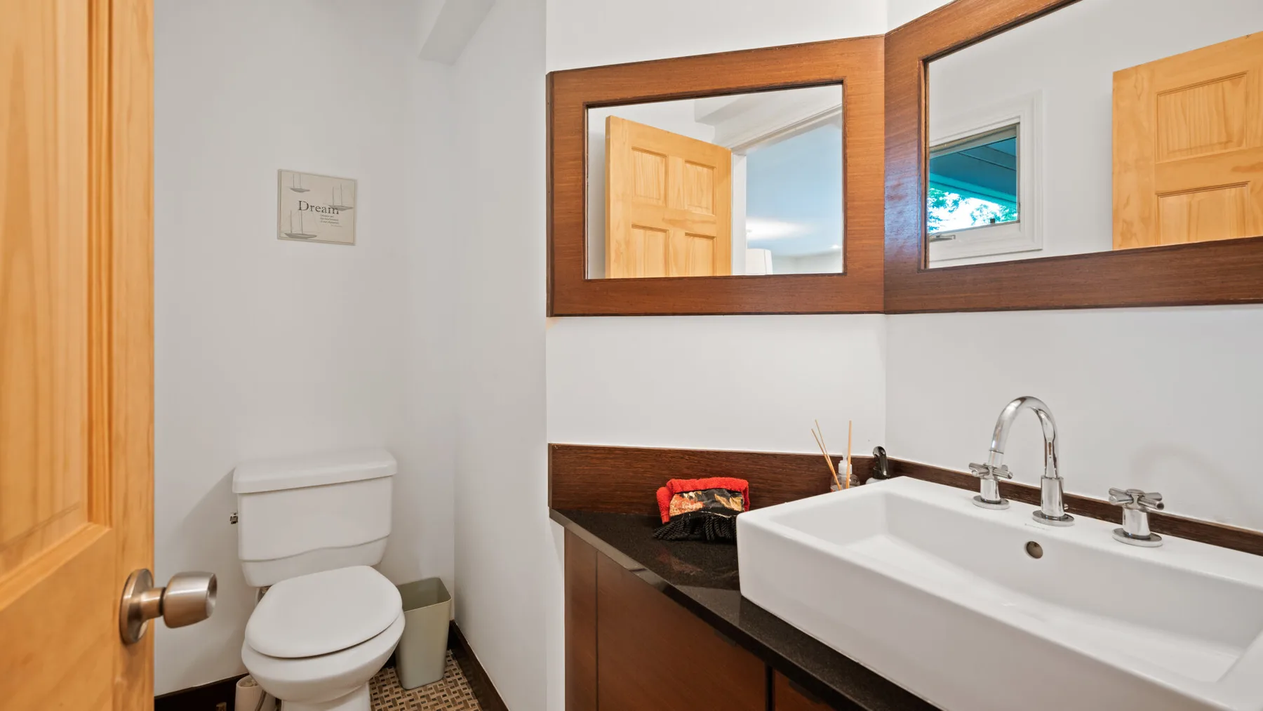 A bathroom with a white sink, wooden vanity, and toilet.