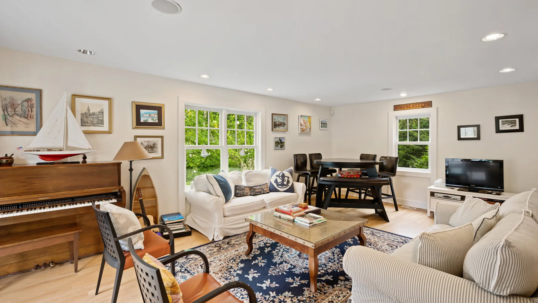 A bright living room with seating, a coffee table, and a piano.