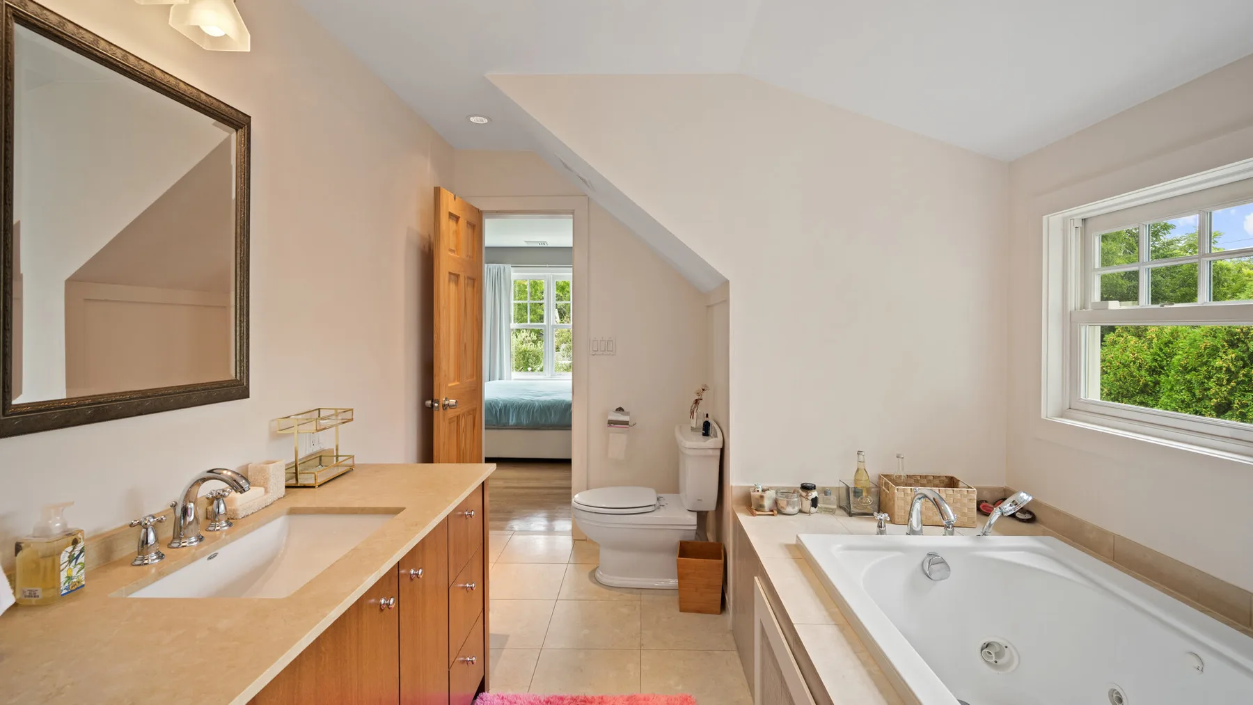 A bathroom with a bathtub, vanity, and an open doorway to a bedroom.