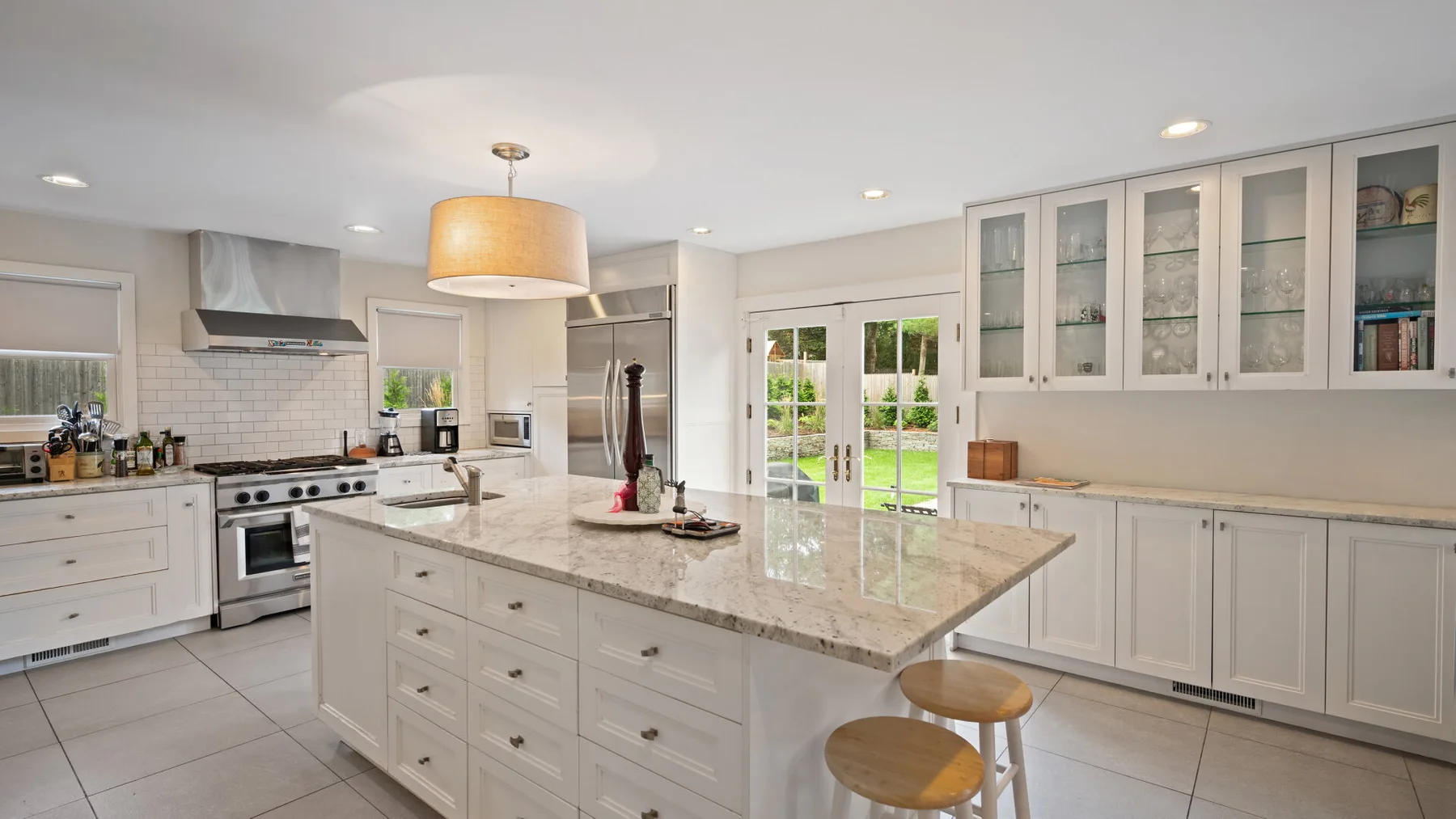 A bright kitchen with a large island and glass-front cabinets.