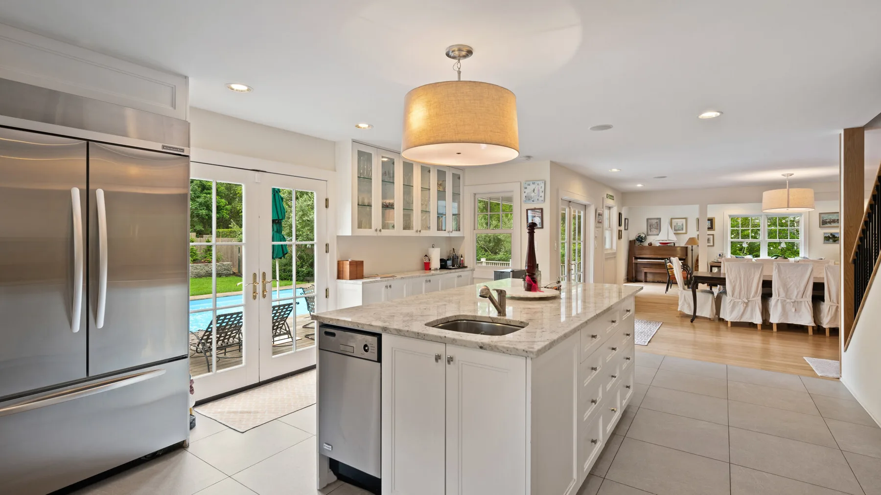 A bright kitchen with a central island opens onto a dining area.