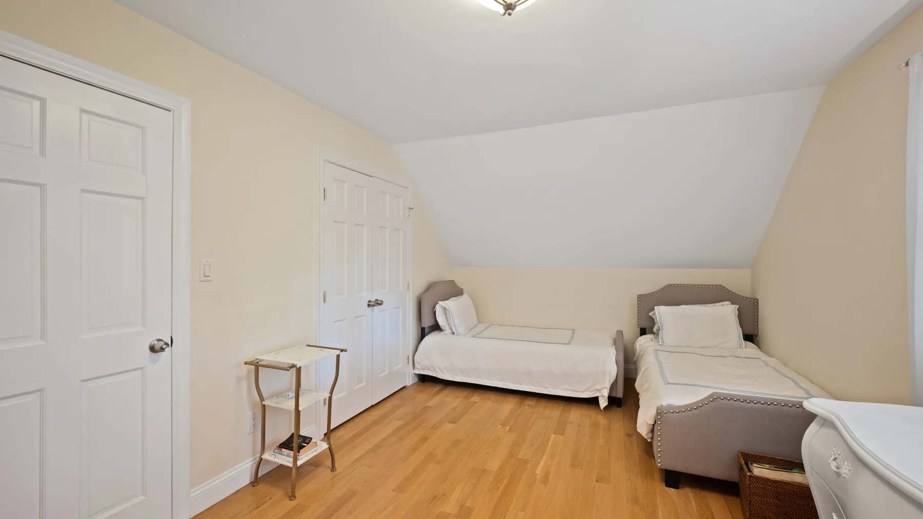 A bright bedroom with two single beds beneath a sloped ceiling.
