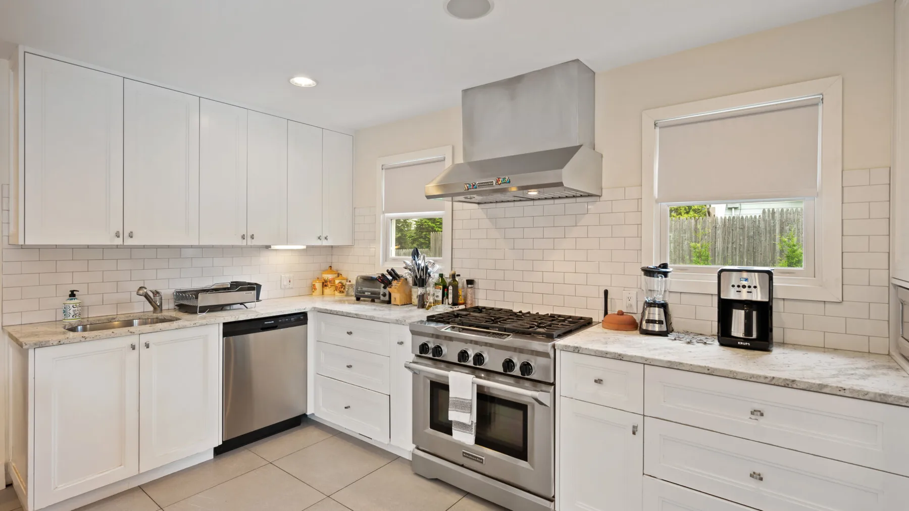 A bright kitchen with white cabinets, a stainless-steel range, and countertop appliances.