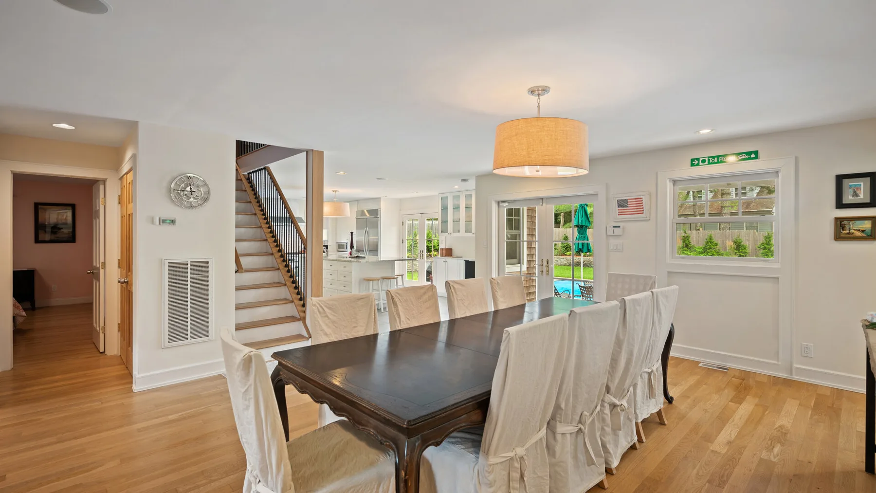 A bright dining area features a large table surrounded by upholstered seating.