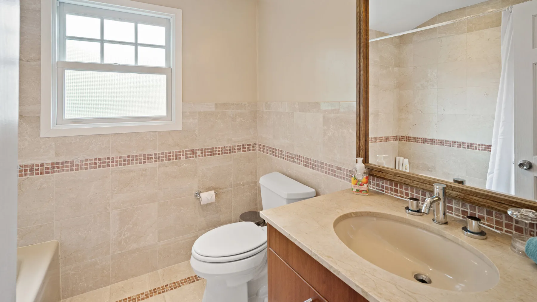 A bathroom with a sink, toilet, and large mirror.