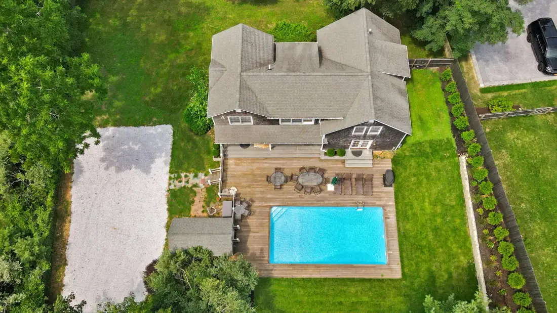 An aerial view of a house with a swimming pool and surrounding lawn.