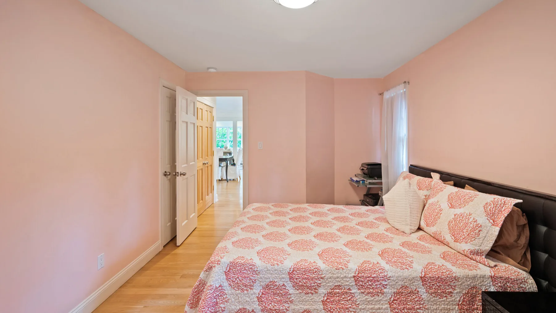 A bedroom with a patterned bedspread and an open doorway.