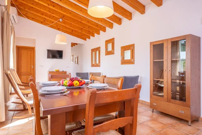 A dining area with a wooden table and chairs beneath a beamed ceiling.