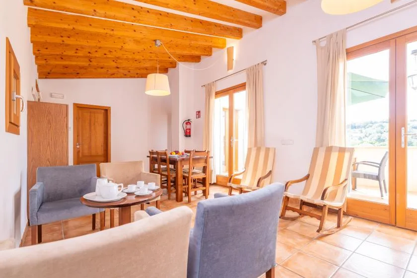 A bright living and dining area with seating, a dining table, and large windows.