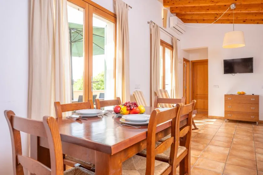 A dining area with a wooden table and chairs beside large windows.