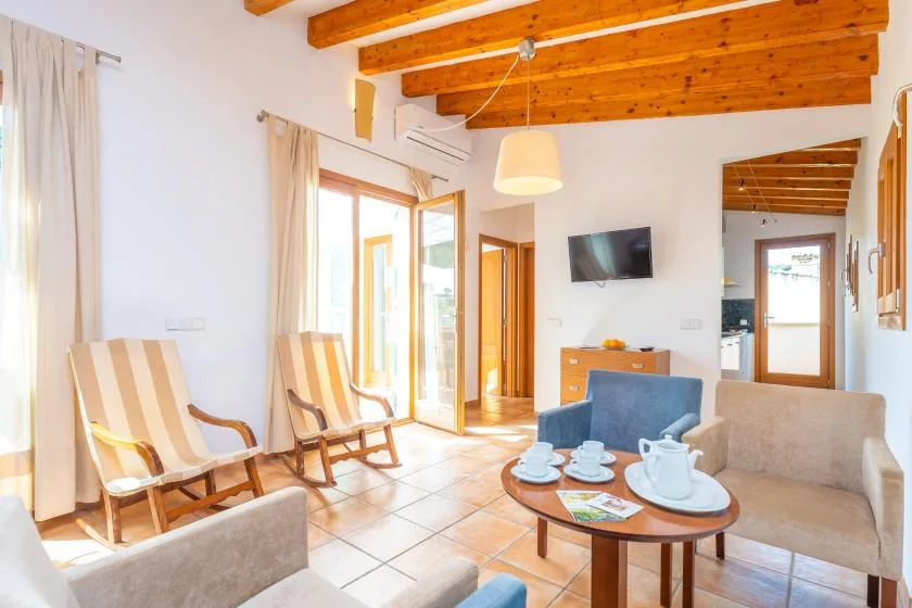 A bright living room with seating, a coffee table, and exposed wooden ceiling beams.