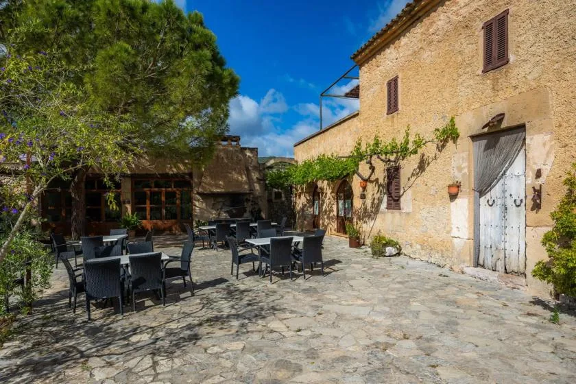 A stone courtyard with outdoor dining tables beside a rustic building.