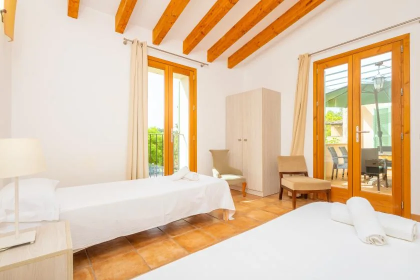 A bright bedroom with white bedding and wooden-framed glass doors.