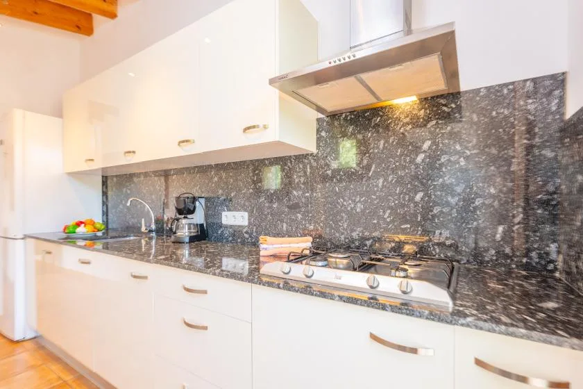 A bright kitchen with white cabinets, a dark countertop, and a gas cooktop.