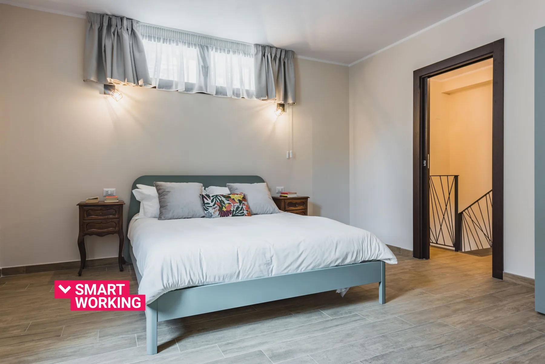 Un dormitorio con una cama bien hecha y una ventana alta con cortinas.