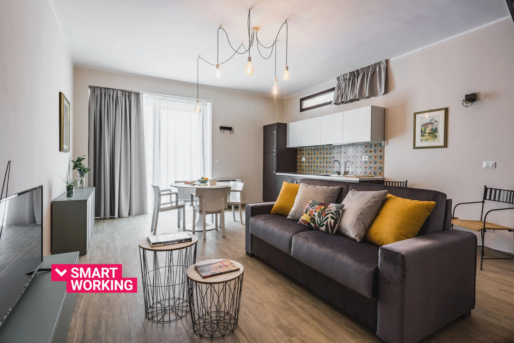 Sala de estar con sofá, mesa de comedor y cocina abierta.