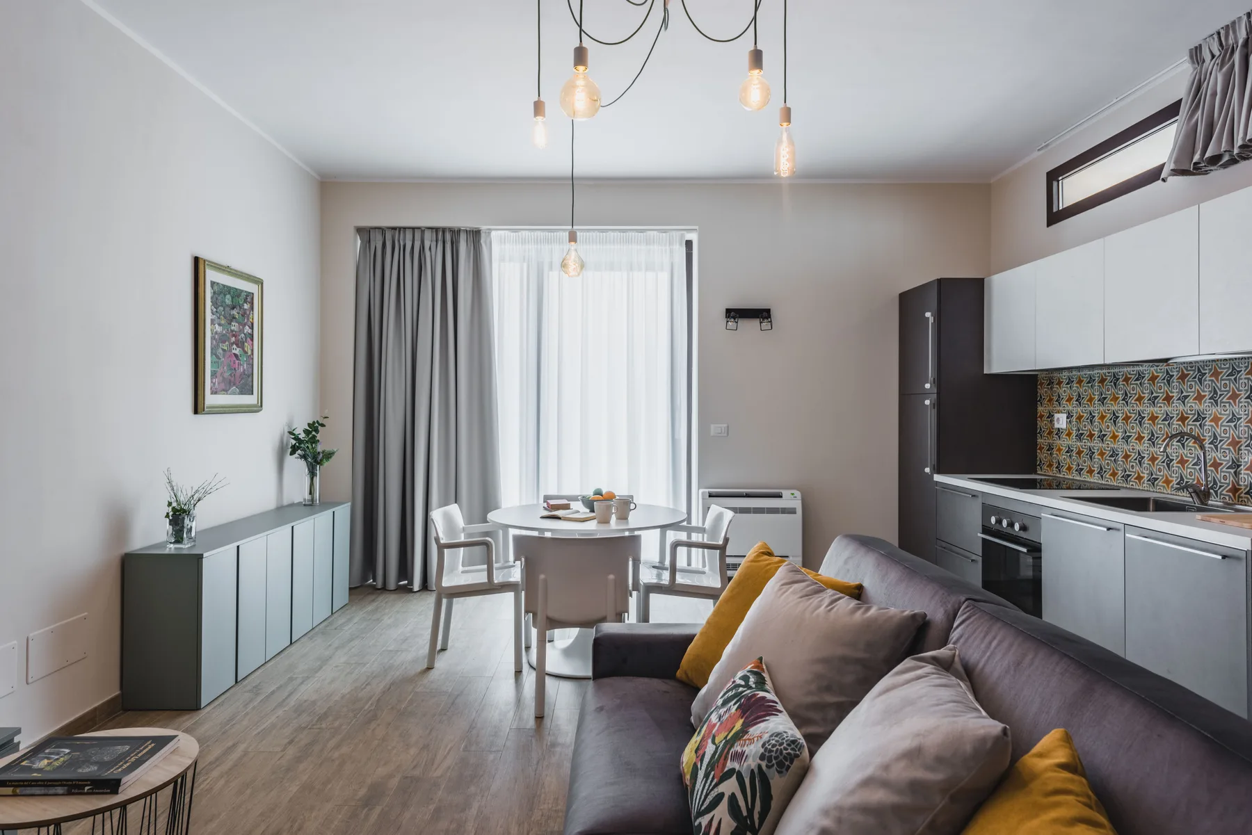 Una luminosa sala de estar y cocina diáfana con mesa de comedor y asientos.