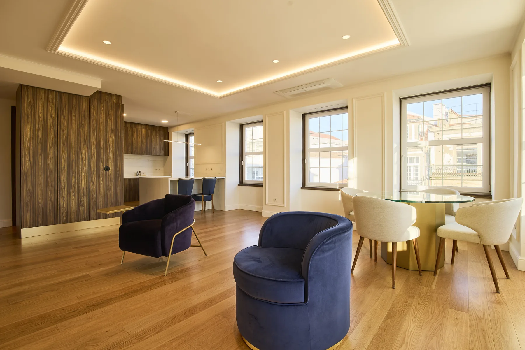 A bright open-plan living and dining area with blue seating and large windows.