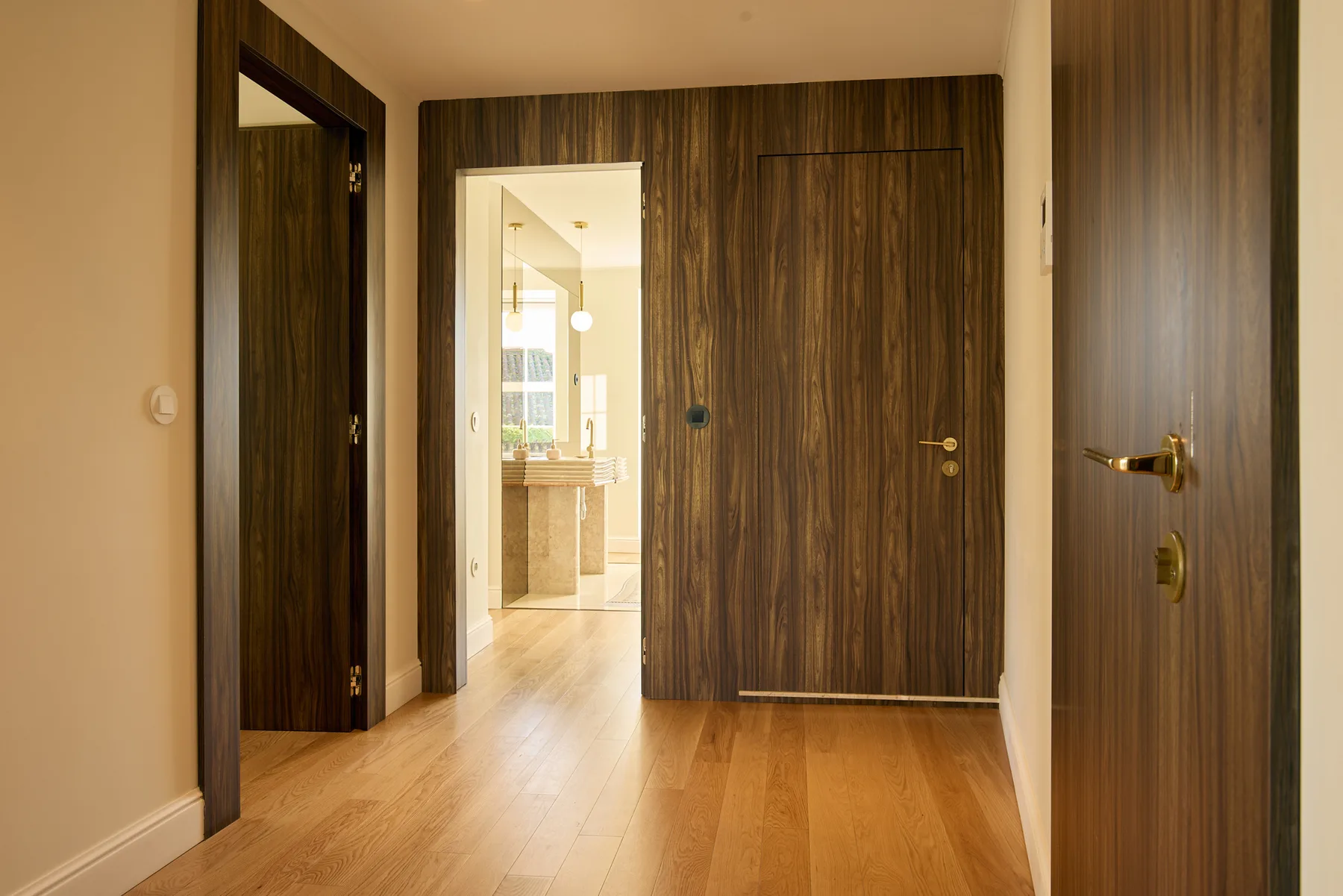 A wood-floored hallway leads to an open, bright living area.