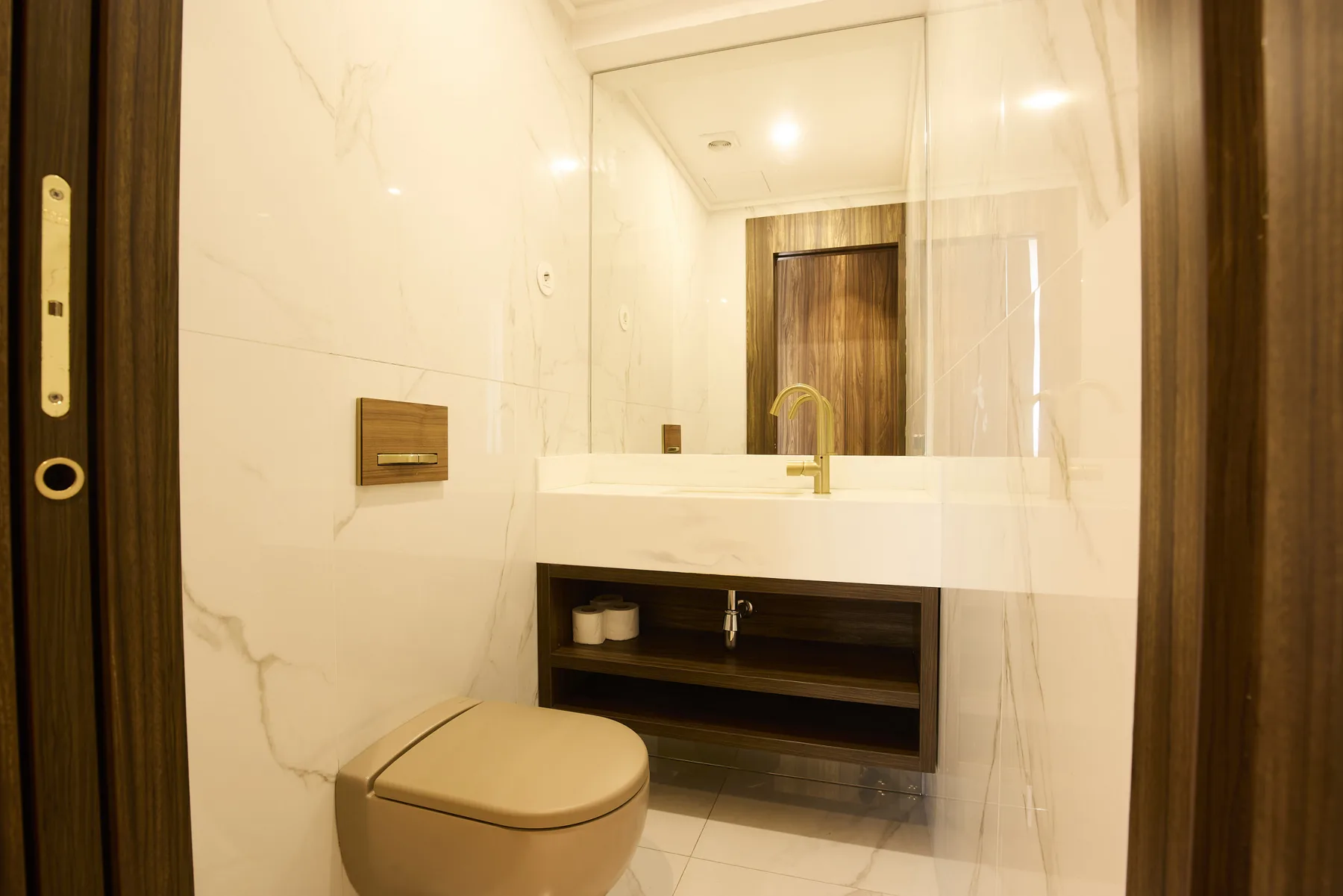 A bright bathroom with a toilet, sink, and large mirror.