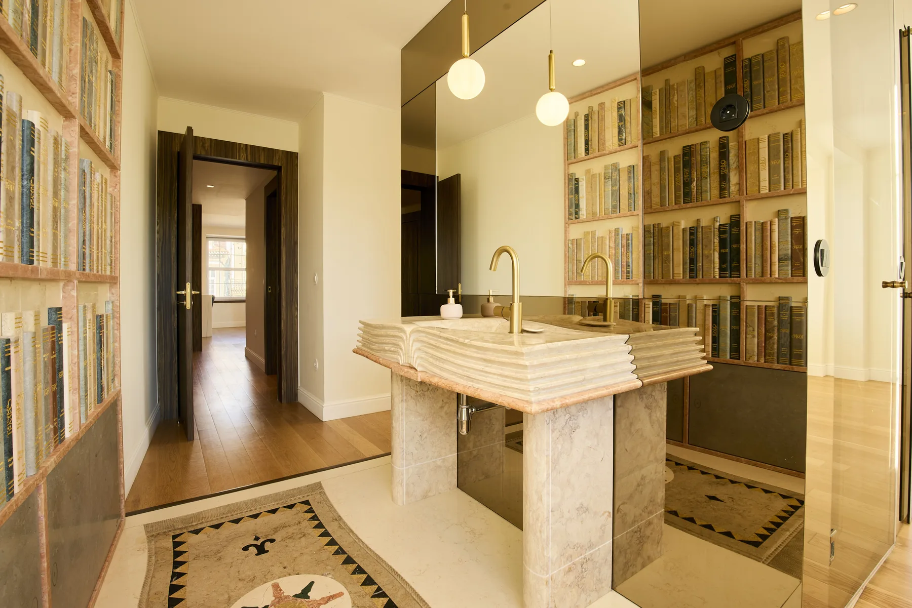 A bright kitchen with a central island, pendant lights, and built-in bookshelves.