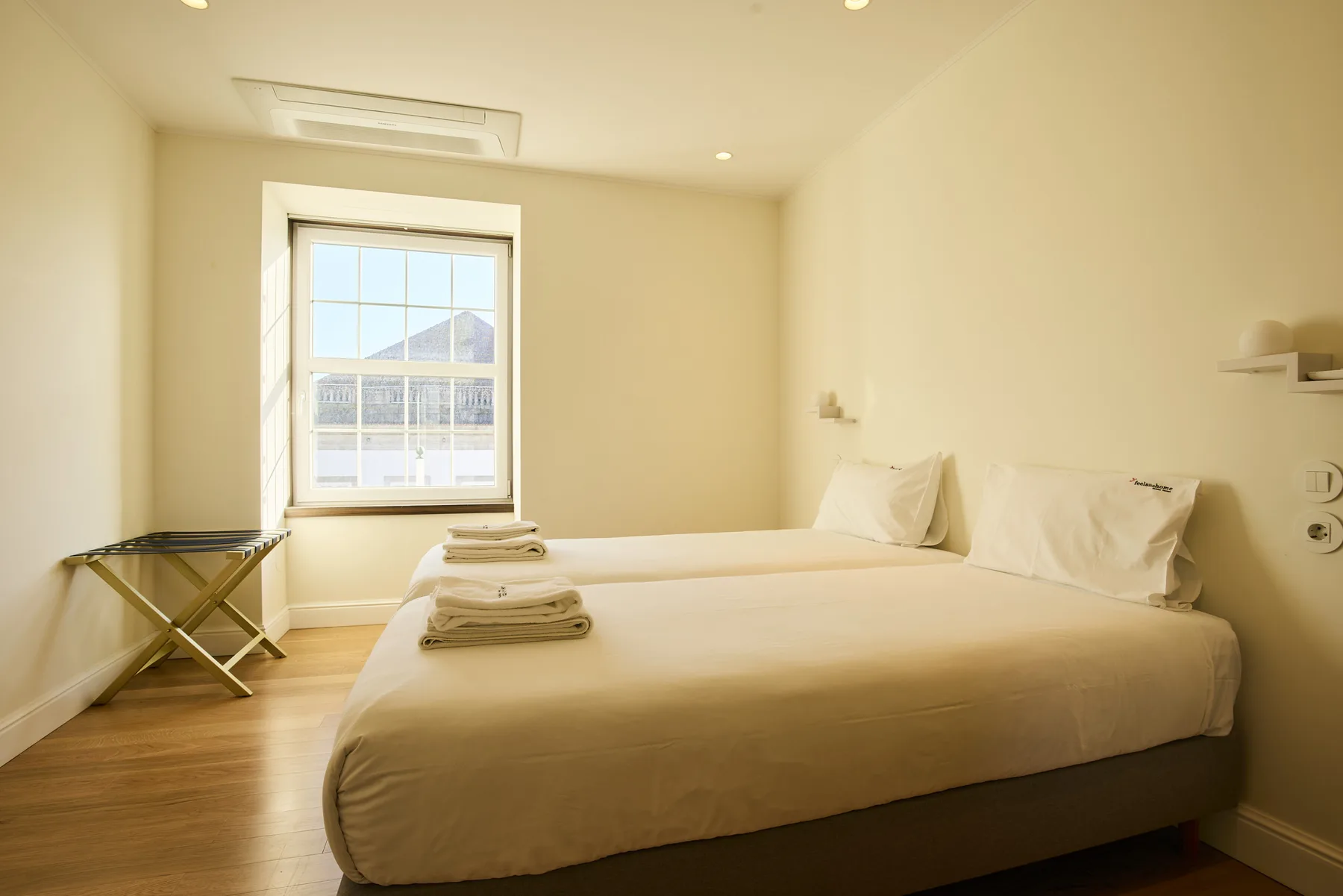 A bright bedroom with a neatly made bed and a large window.