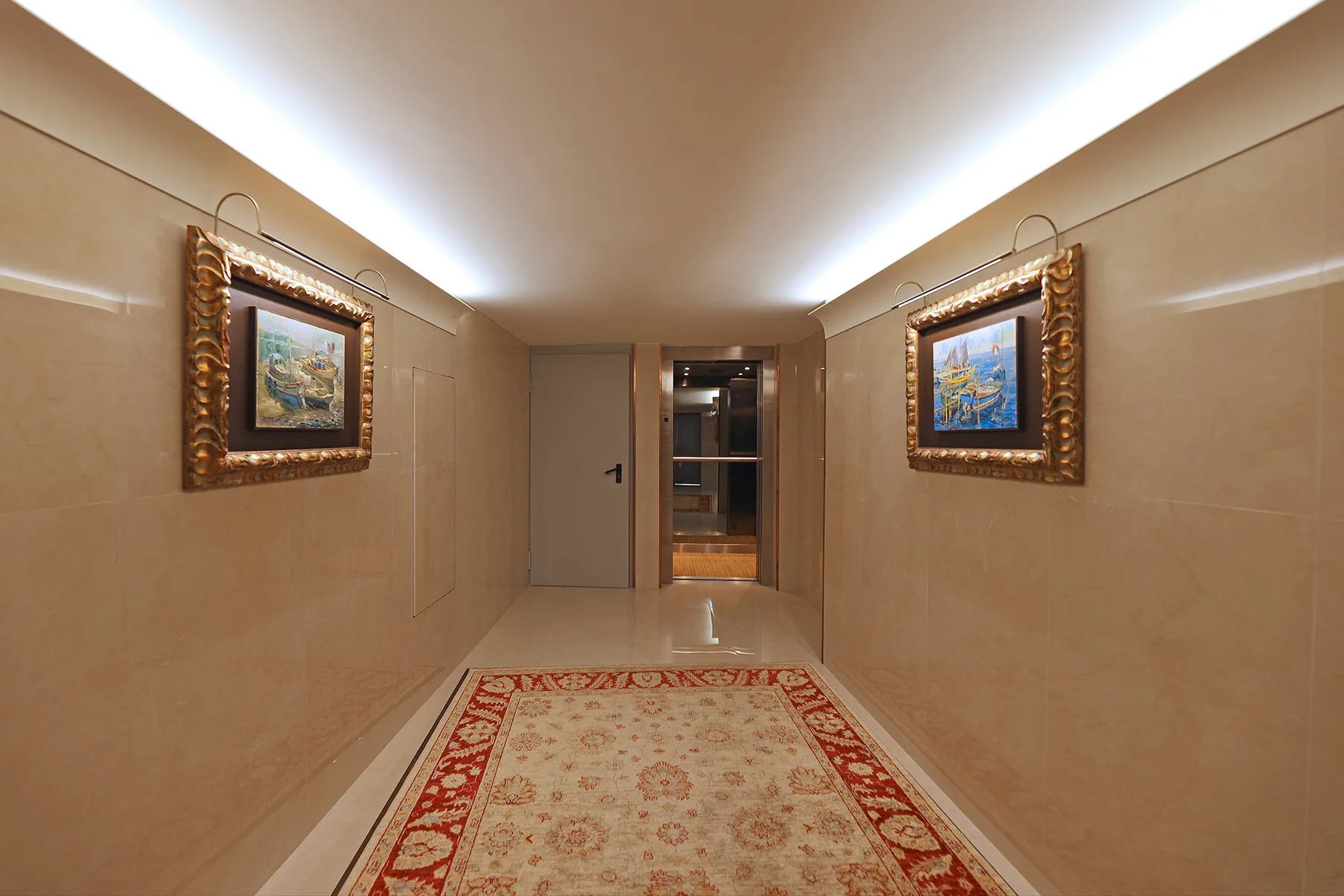 A beige hallway with framed artwork and a patterned rug.