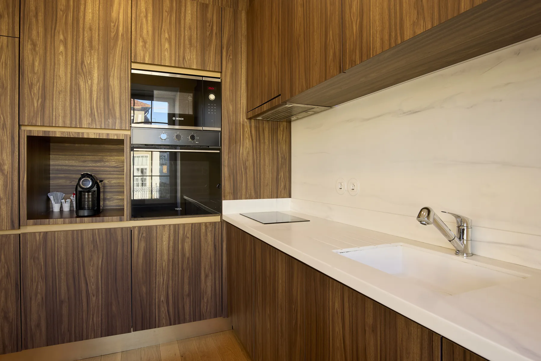 A modern kitchen with wood cabinetry, built-in appliances, and a white countertop.