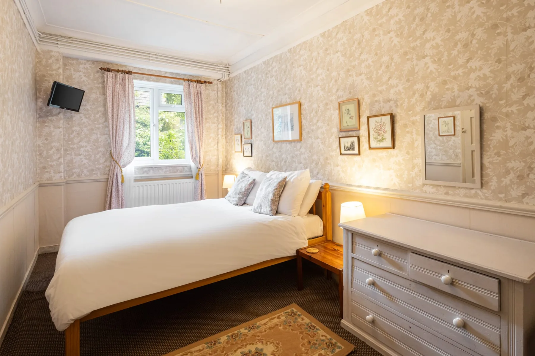 A bedroom with a bed, a window, and a chest of drawers.