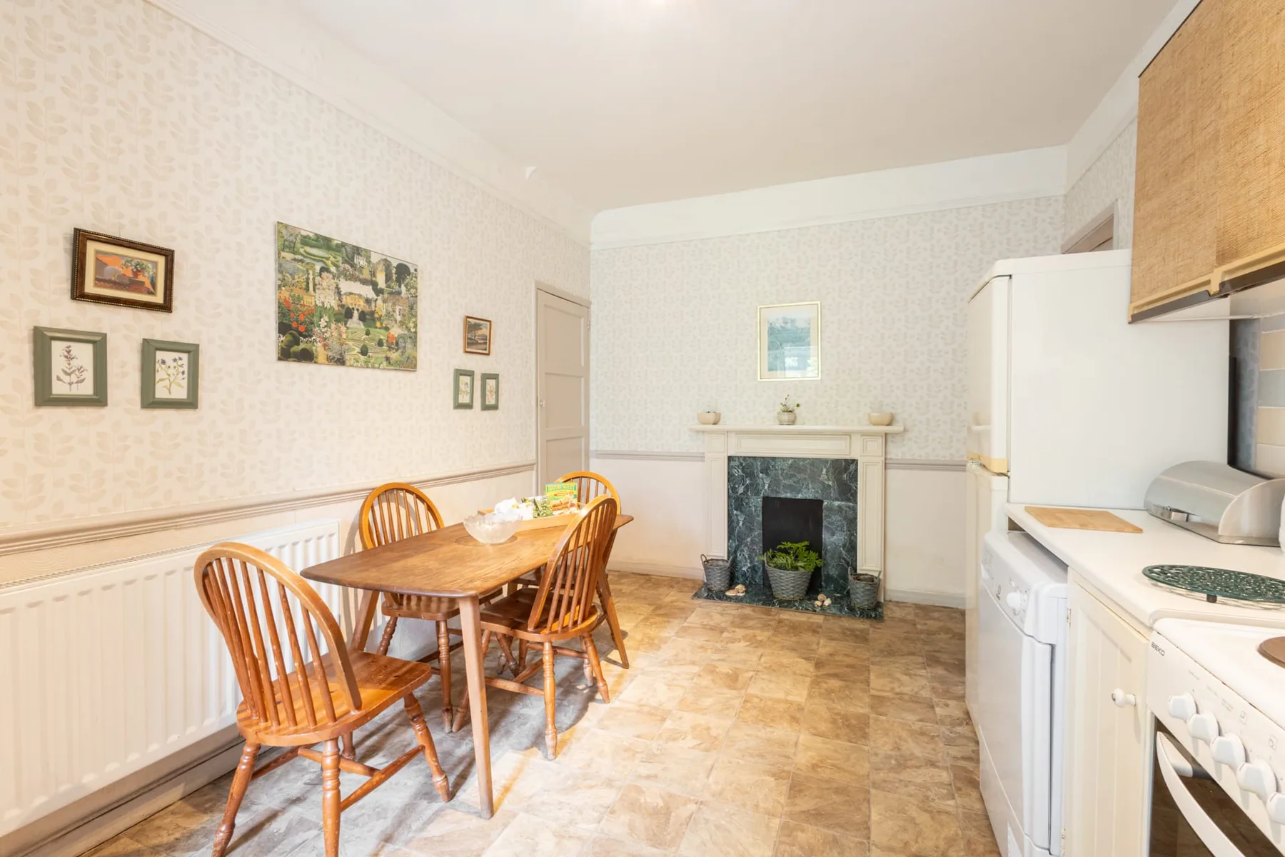 A dining area with a wooden table sits beside a bright kitchen.