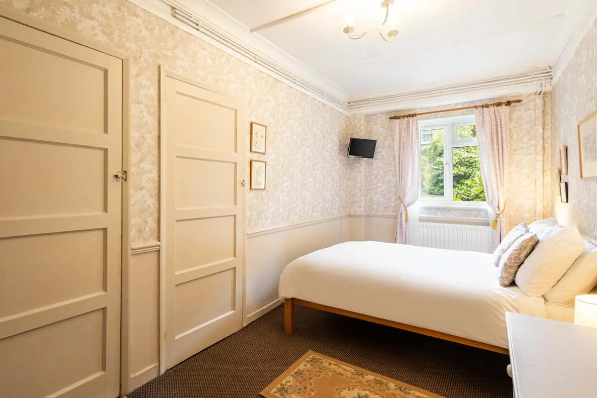 A bedroom with a neatly made bed and a window.