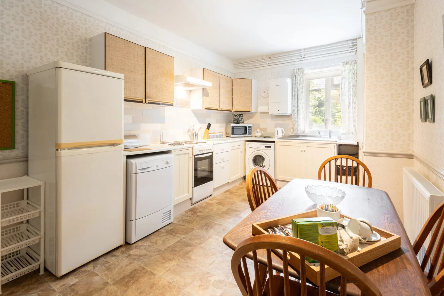 A bright kitchen with light cabinetry, appliances, and a dining table.