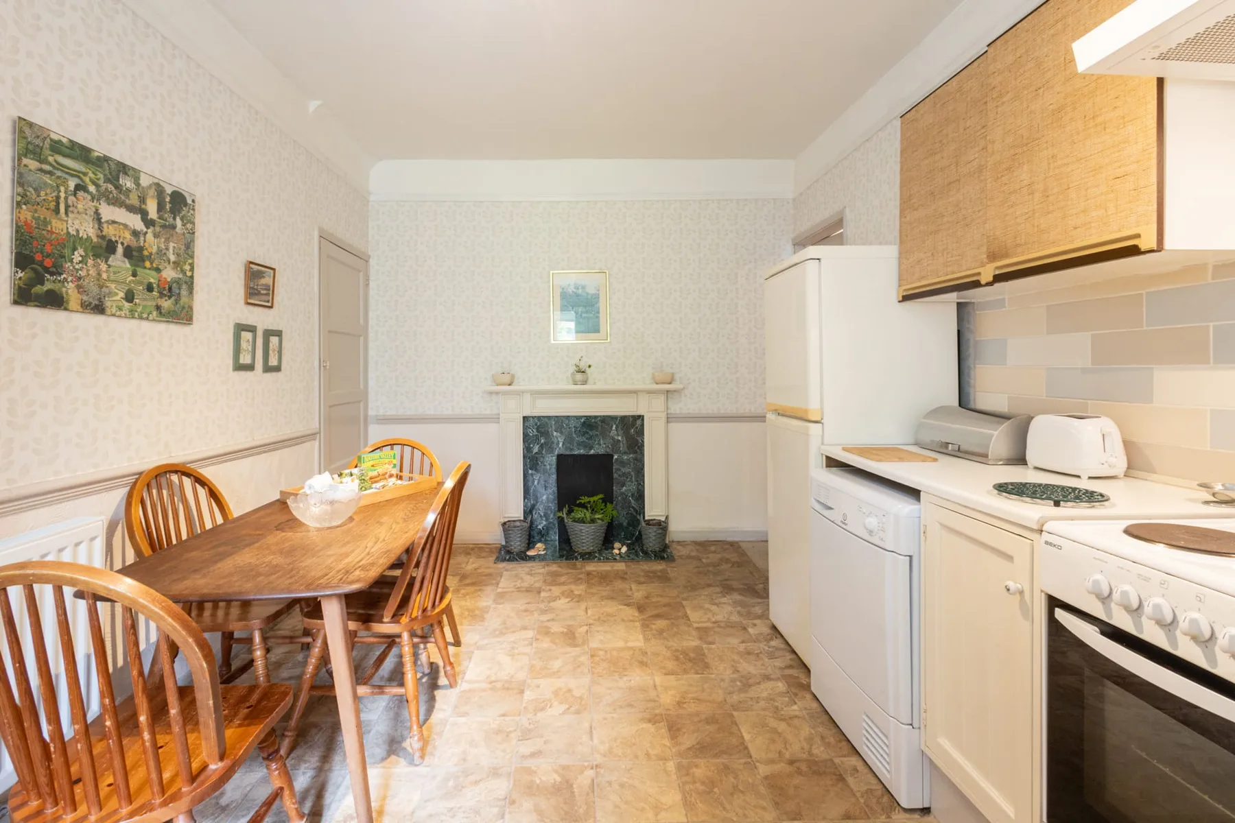 A dining and kitchen area with a wooden table and fireplace.