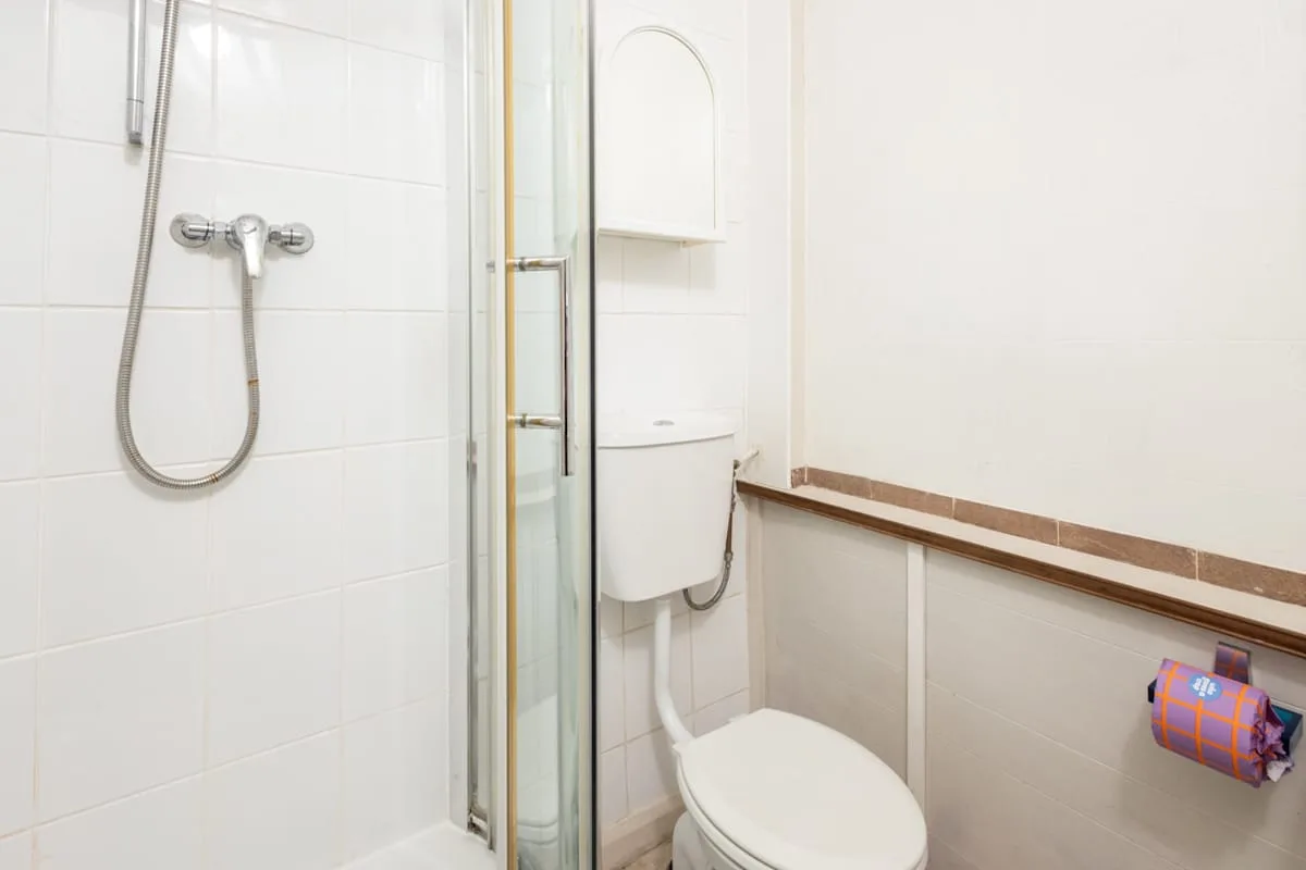 A bright bathroom with a shower, toilet, and wall-mounted sink.
