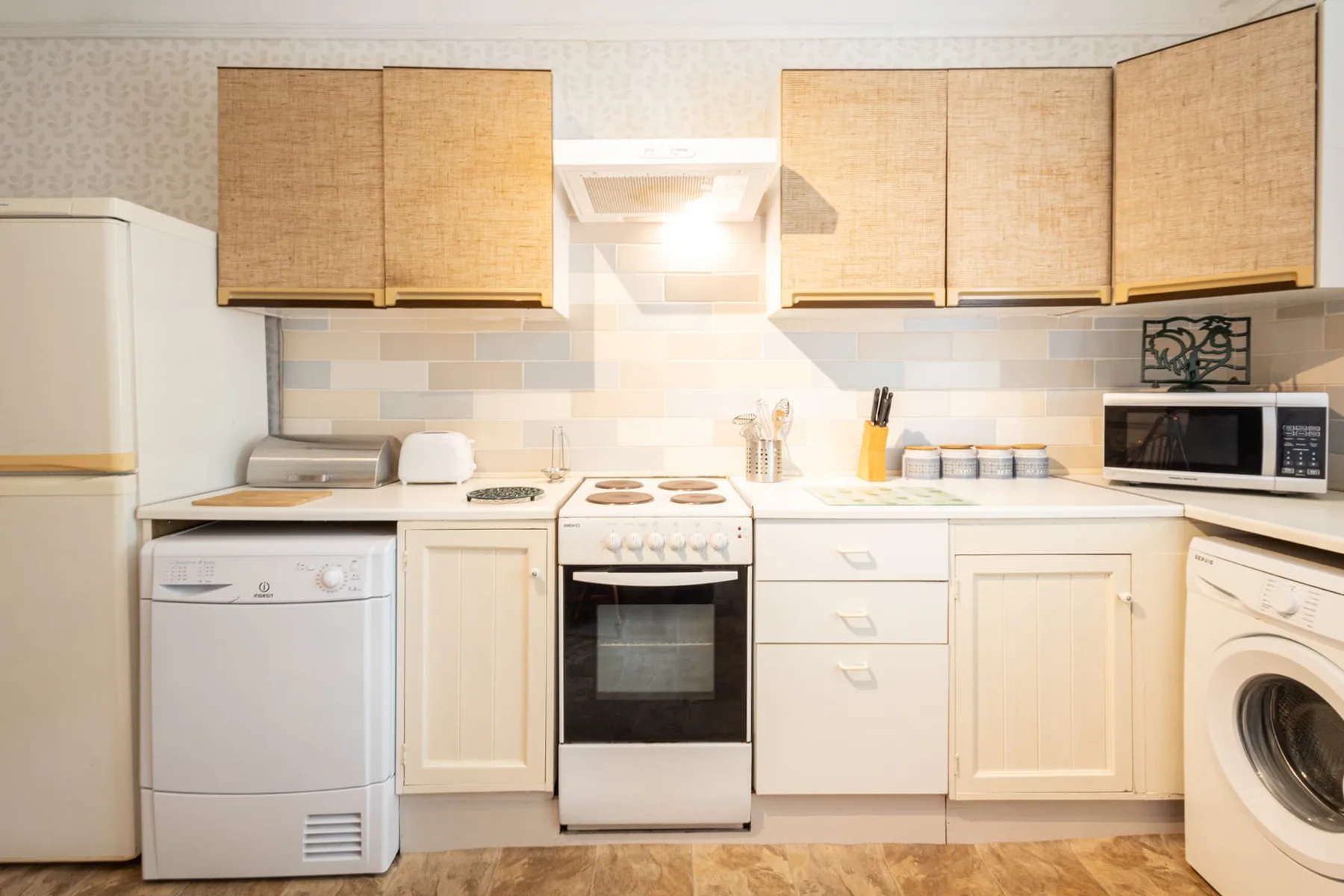 A kitchen with light wood cabinets, a stove, and a microwave.