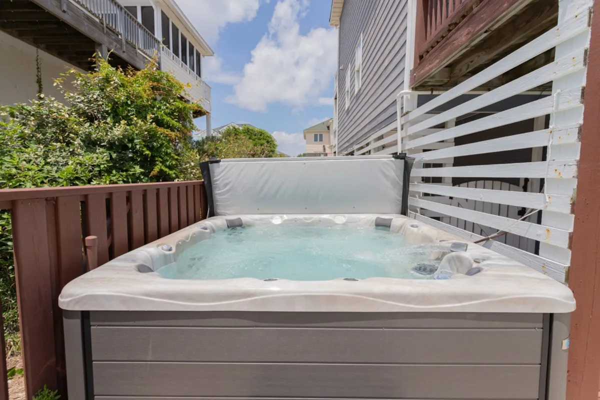 Una bañera de hidromasaje al aire libre está en una terraza estrecha entre edificios.