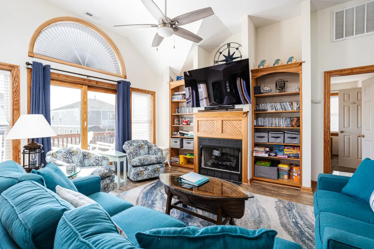 Una sala luminosa con asientos color turquesa y una chimenea bajo un televisor.