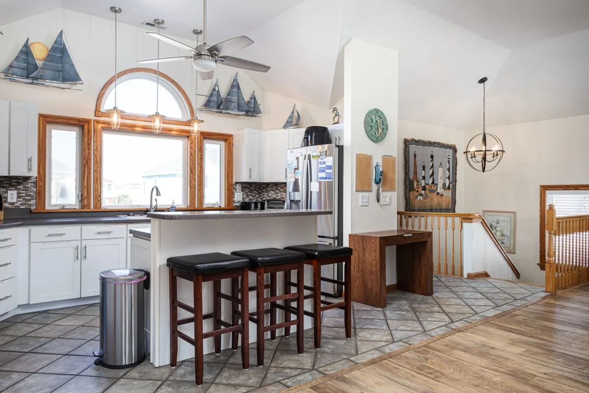 Una cocina abierta con barra de desayuno junto a una escalera y decoración náutica.