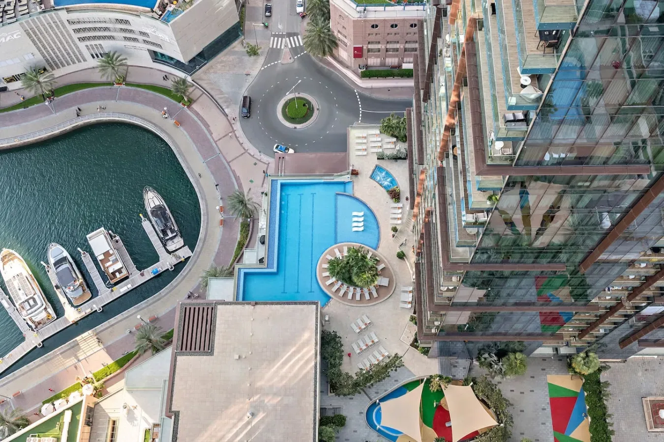 Vista aérea de edificios junto al agua, una marina y una piscina azul.