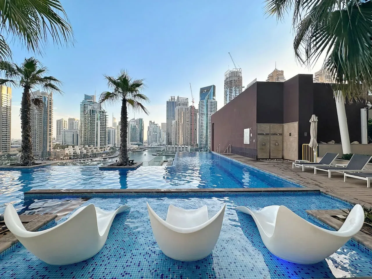 Una piscina en la azotea ofrece vistas del perfil urbano, con asientos blancos junto al agua.